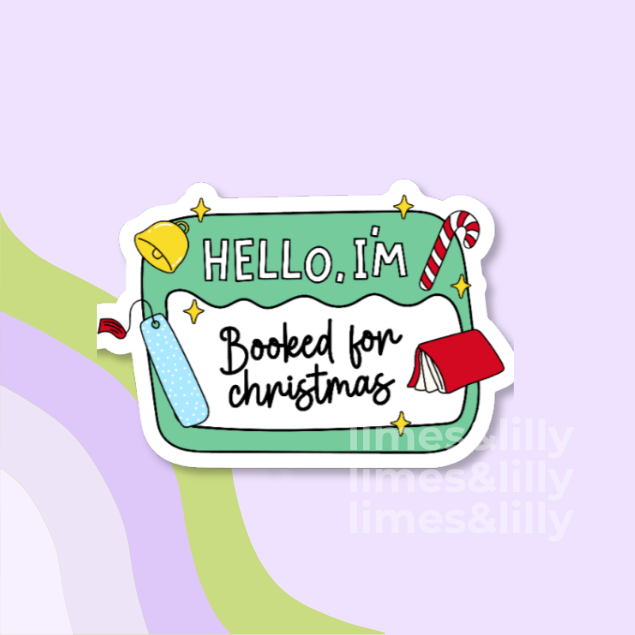 A die-cut sticker with a white border and a festive Christmas design, featuring the text 'HELLO, I'M Booked for christmas' on a mint green background with illustrations of a bell, candy cane, gift tag, and book, shown on a pastel purple background.