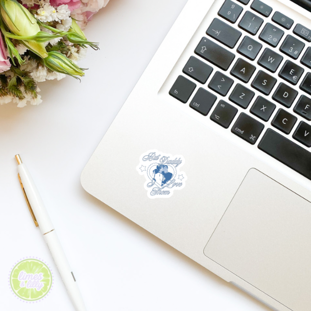 Laptop with a sticker on a white surface with flowers and a pen.