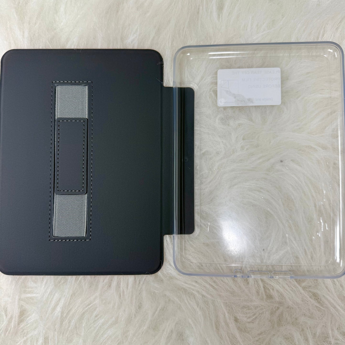 Black leather-bound book with a clear plastic cover on a textured surface