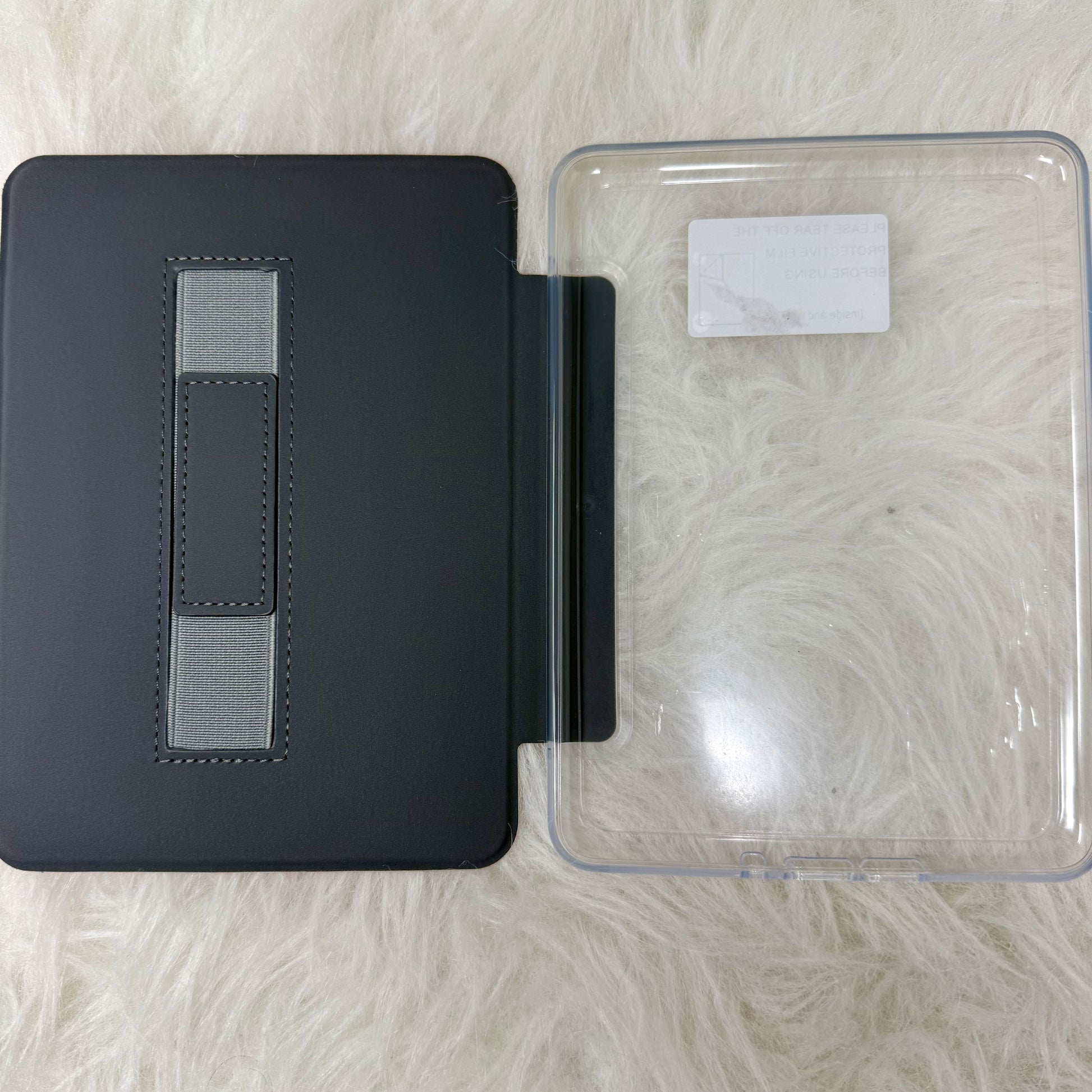 Black leather-bound book with a clear plastic cover on a textured surface