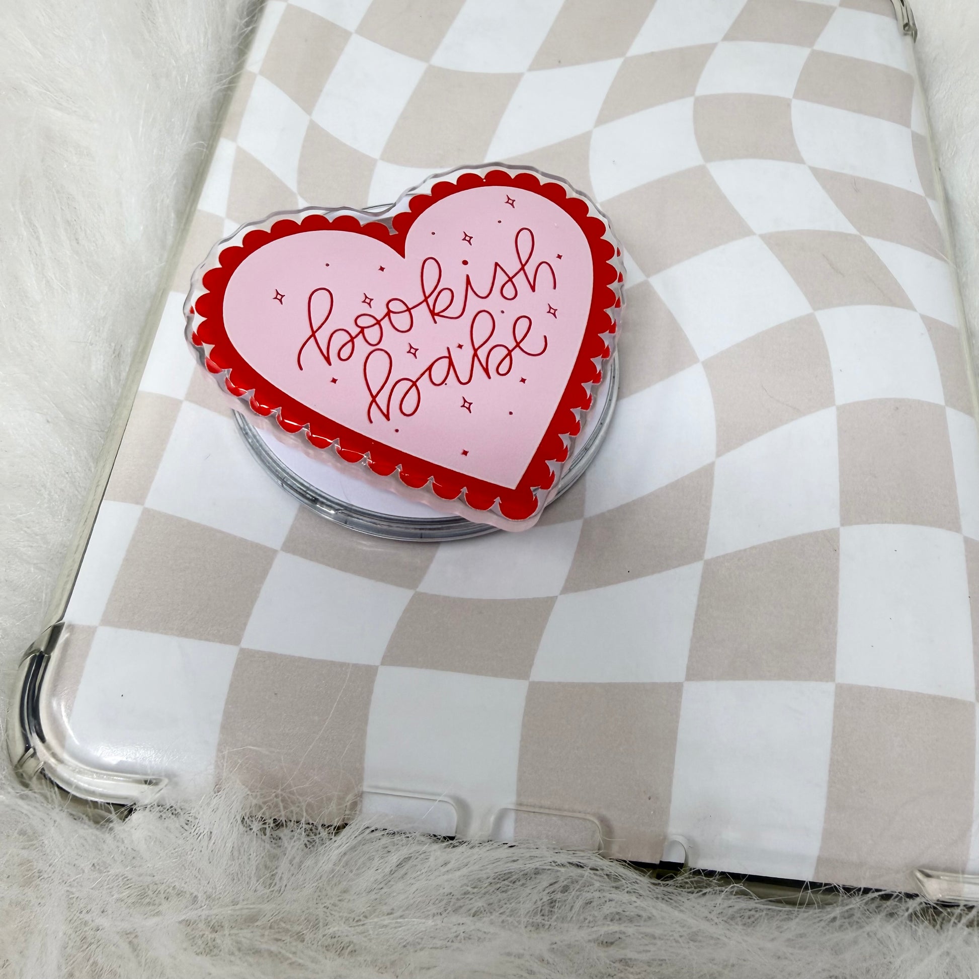 Heart-shaped pink and red object with 'bookish babe' text on a checkered surface