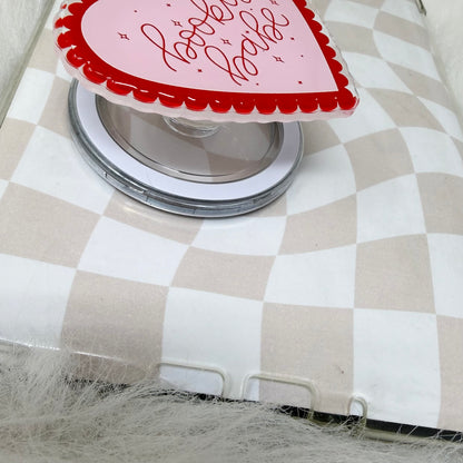 Heart-shaped glass with red and white design on a checkered tablecloth