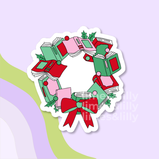 A die-cut sticker featuring a festive book wreath design with green, pink, and red books, holly leaves, and a red bow, shown on a pastel purple background with abstract green and lavender shapes.