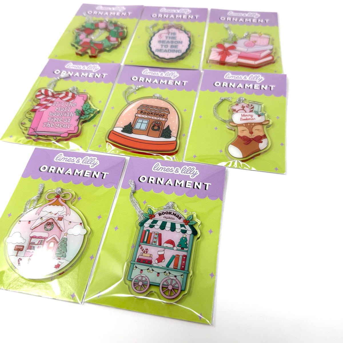 8 packaged Christmas ornament enamel pins arranged on a white background. Each pin is mounted on a bright green card with a purple header that reads 'lovely ORNAMENT.