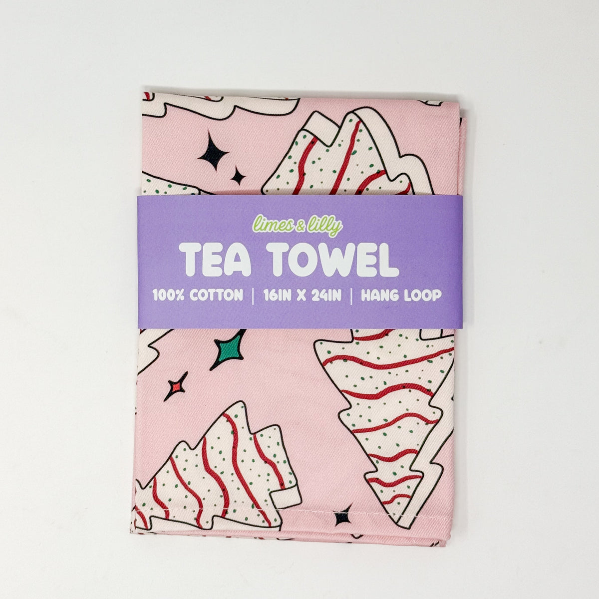 Pink Christmas tea towel with frosted Christmas tree cake illustrations and colorful holiday sparkles