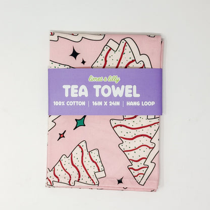 Pink Christmas tea towel with frosted Christmas tree cake illustrations and colorful holiday sparkles