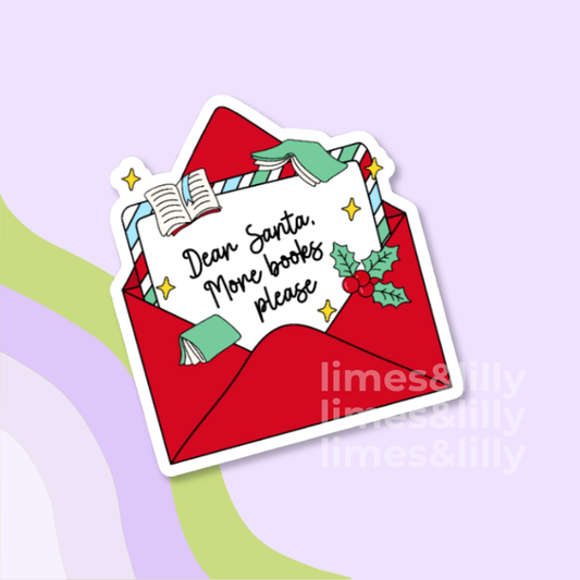 A die-cut sticker featuring a red envelope with a white card that reads 'Dear Santa, More books please' in black script, decorated with an open book, green hands, holly leaves, and small gold stars. The sticker is shown on a light lavender background with abstract pastel shapes and a faint 'limes&lilly' watermark.
