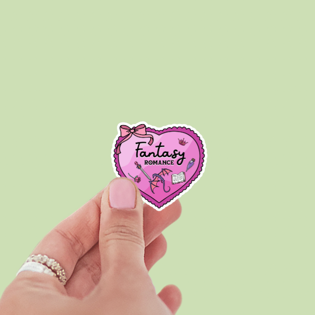 Heart-shaped sticker with 'Fantasy Romance' text held by a hand on a light green background