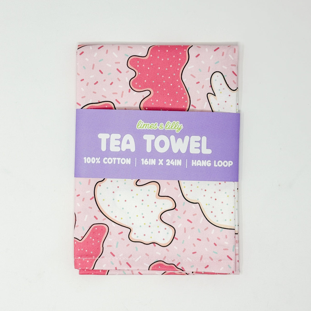 Pink cotton tea towel featuring pink and white frosted animal cookies with colorful sprinkles