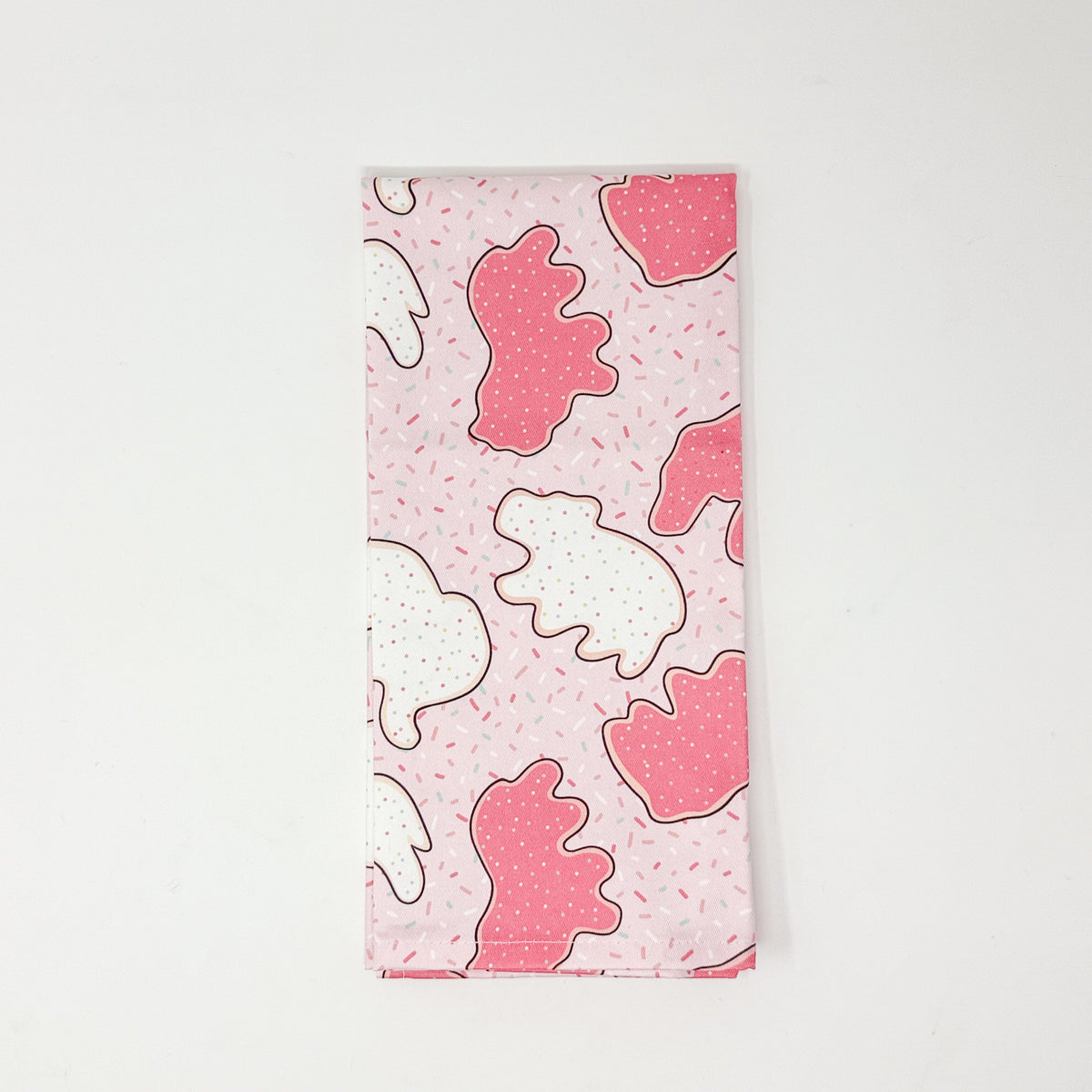 Pink cotton tea towel featuring pink and white frosted animal cookies with colorful sprinkles