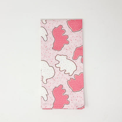 Pink cotton tea towel featuring pink and white frosted animal cookies with colorful sprinkles