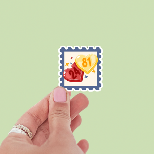 Hand holding a decorative stamp with hearts and numbers on a light green background