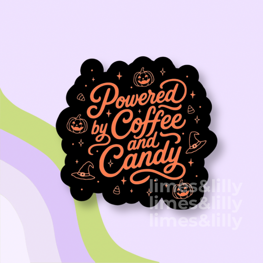 A scalloped black sticker or decal with orange script text reading 'Powered by Coffee and Candy' and small Halloween illustrations, shown on a pastel lavender background with abstract green and lavender shapes.