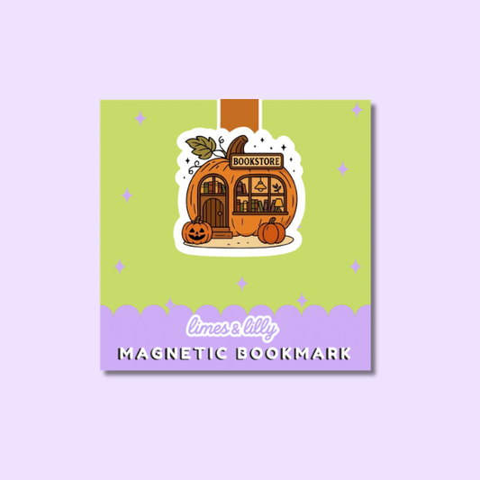 A square product shot of a decorative magnetic bookmark on a light lavender background. The bookmark has a lime green upper section with small star accents, a purple lower band with the text 'limes & lilys MAGNETIC BOOKMARK,' and a central illustration of a pumpkin-shaped bookshop with a jack-o'-lantern in front.