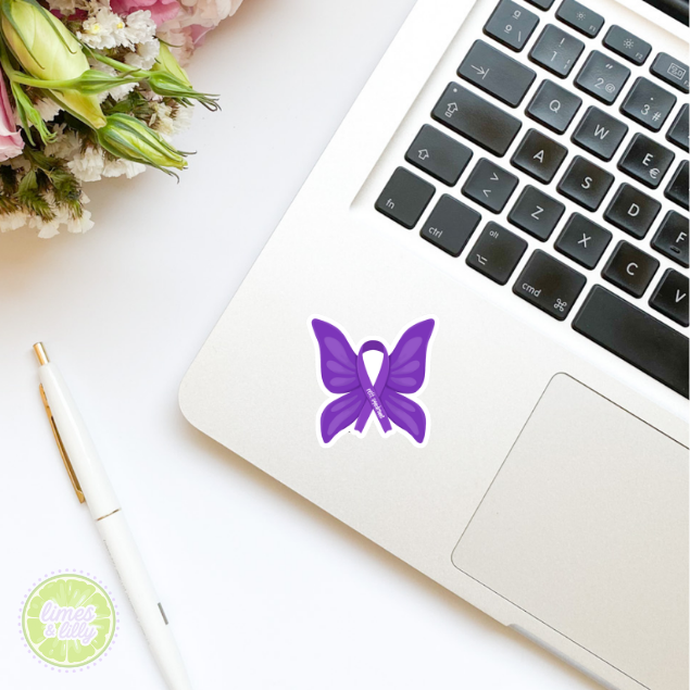 Laptop with a purple butterfly sticker on a white surface with flowers and a pen.