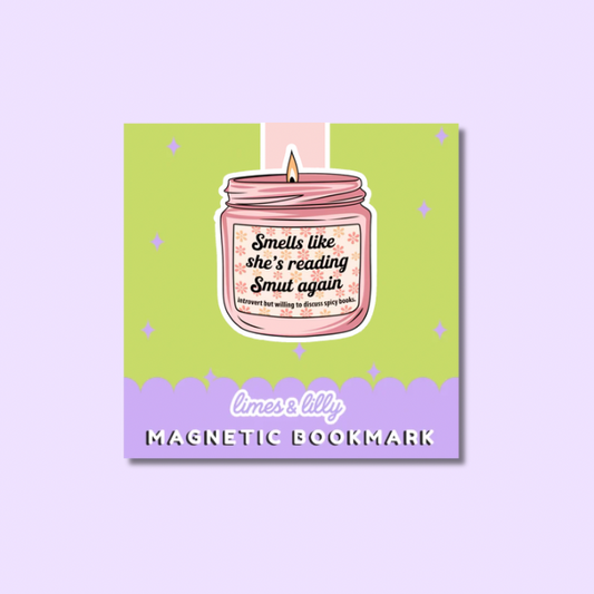 A square magnetic bookmark card featuring a pink candle jar illustration with the phrase 'Smells like she's reading Smut again' and 'limes & lily MAGNETIC BOOKMARK' on a light purple background.
