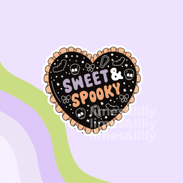 A heart-shaped sticker with a scalloped peach border, featuring a black background decorated with white skulls, candy corn, bats, and stars, with the words 'SWEET & SPOOKY' in pastel purple, pink, and orange lettering. The sticker is shown on a light purple background with abstract wavy stripes in green and lavender.