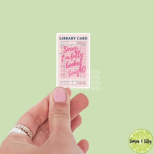May include: A pink library card with the text 'LIBRARY CARD' in blue at the top. The card has a pink and white striped design. The text 'Sorry, I'm fully booked tonight!' is written in pink cursive font. The card has the number '031211' printed in black at the top and bottom.