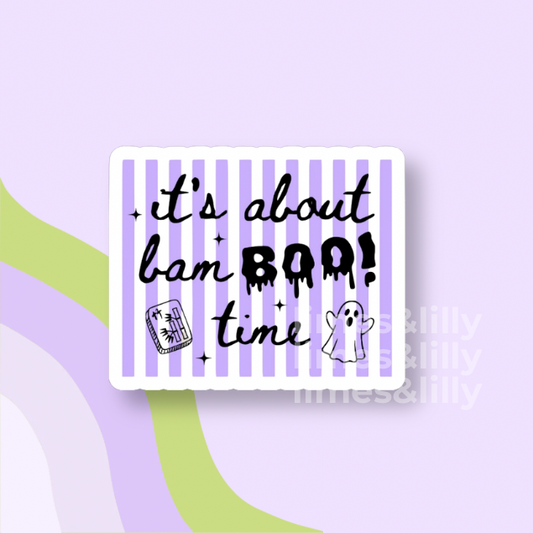 A rectangular sticker with rounded corners featuring a white border, lavender and white vertical stripes, and black text that reads 'it's about bam BOO! time' with small Halloween-themed doodles. The sticker is centered on a light lavender background with abstract green and purple curved shapes.